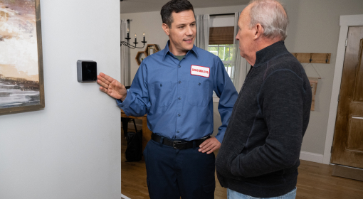 HVAC technician installing a smart thermostat on the wall.