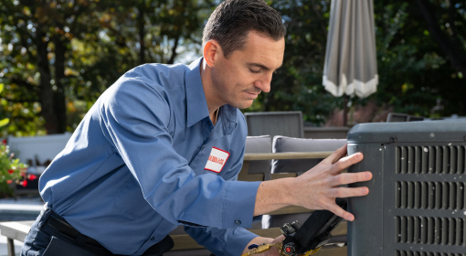 HVAC technician repairing an air conditioning unit outdoors.