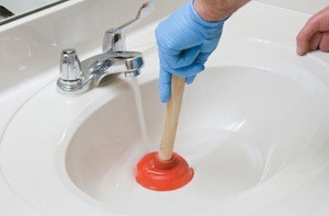 Russo employee plunging a bathroom sink