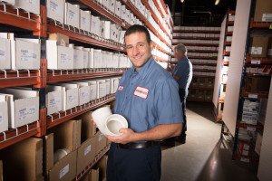 Russo employee posing with a plumbing pipe in the warehouse