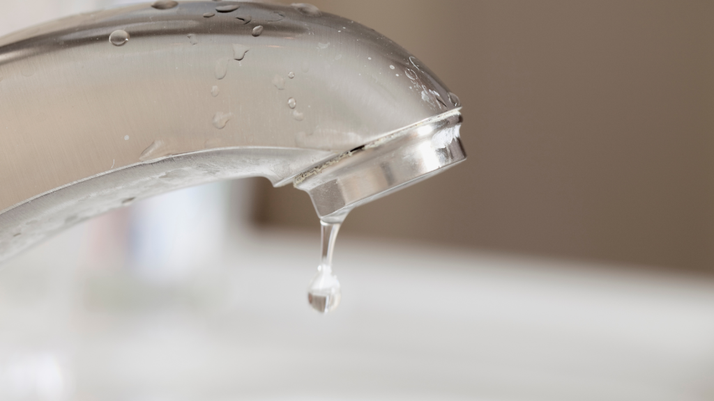 Close-up of water dripping from a chrome bathroom faucet.